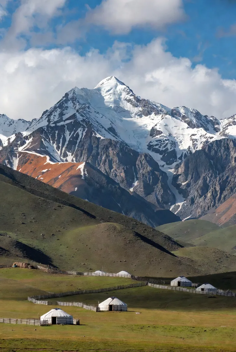 만년설이 덮인 산맥 아래 펼쳐진 키르기스스탄의 초원과 유르트 풍경
