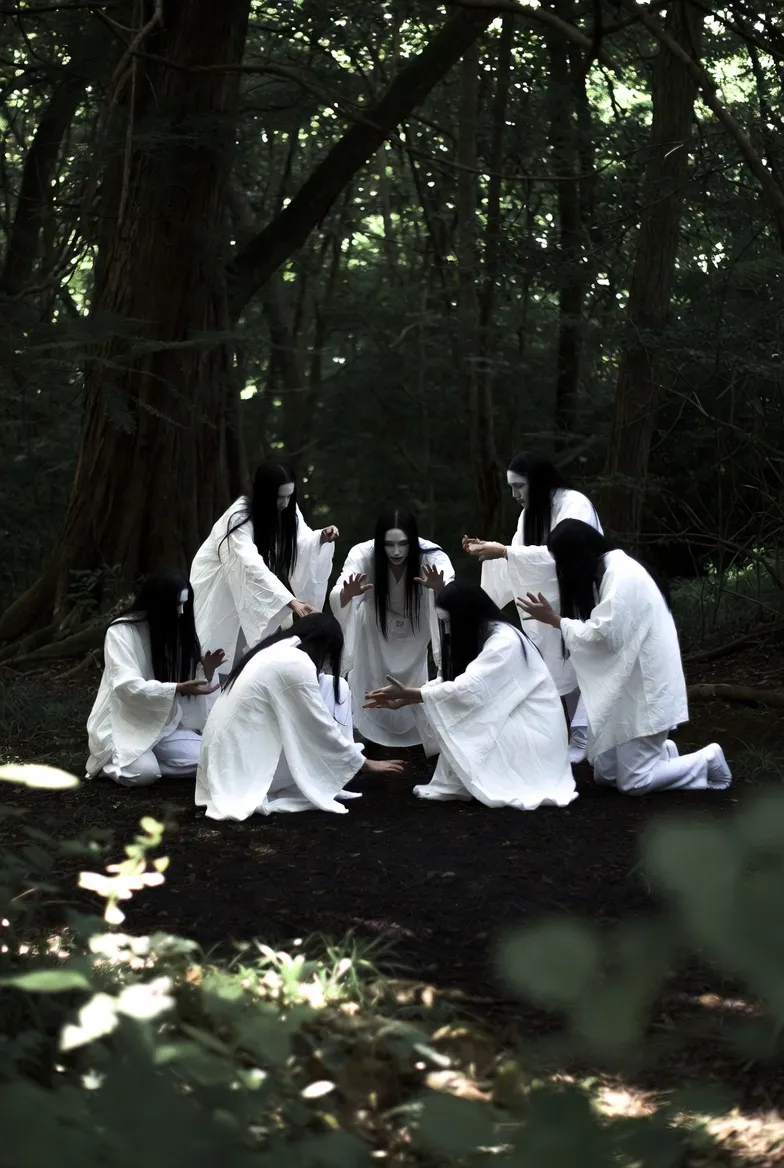 The Goto family in white clothes performing a bizarre ritual in the forest